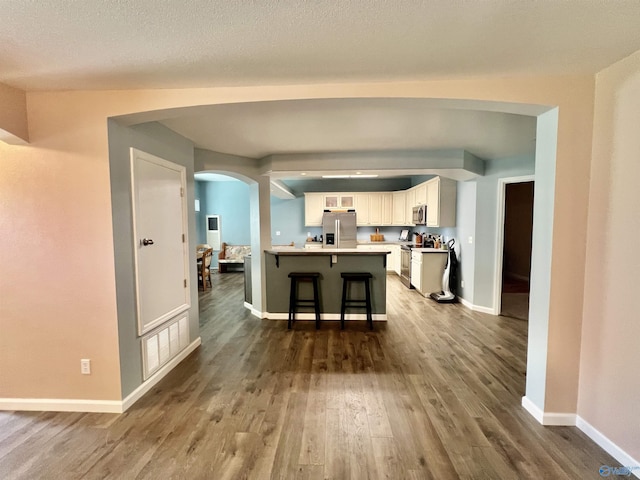 415 County Road 355, Leesburg, AL 35983 - kitchen featuring appliances with stainless steel finishes, wood finished floors, white cabinets, a breakfast bar, and arched walkways