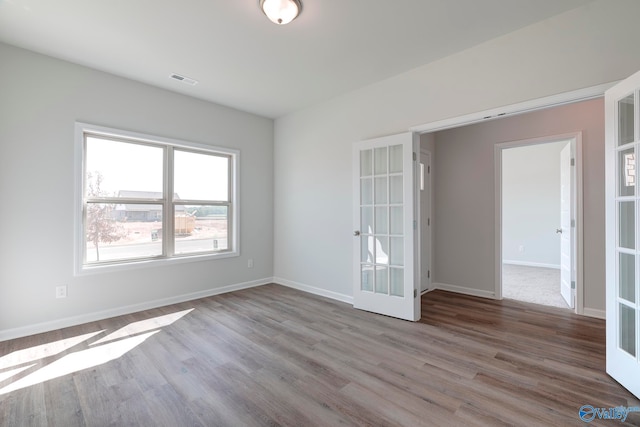 spare room featuring french doors and light hardwood / wood-style flooring