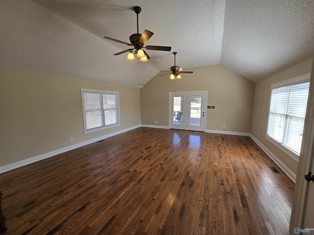 unfurnished living room featuring a healthy amount of sunlight, dark hardwood / wood-style flooring, vaulted ceiling, and a textured ceiling