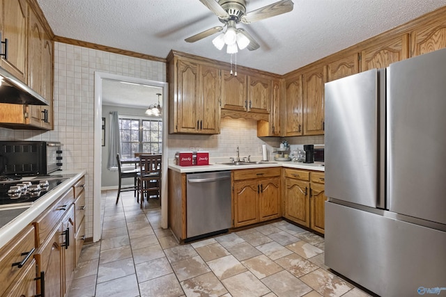 kitchen featuring a textured ceiling, a sink, light countertops, appliances with stainless steel finishes, and brown cabinetry