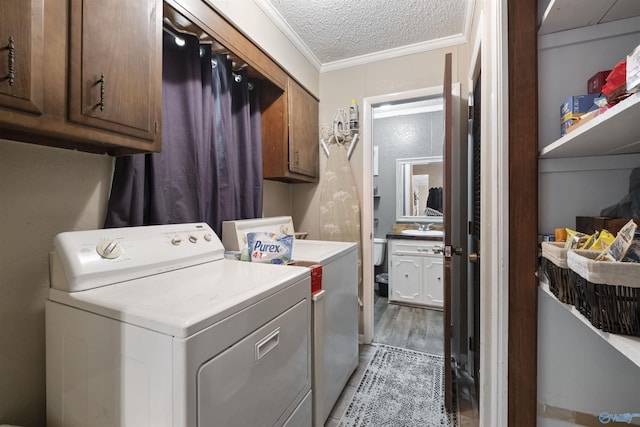 laundry area with a textured ceiling, ornamental molding, washing machine and dryer, and cabinet space