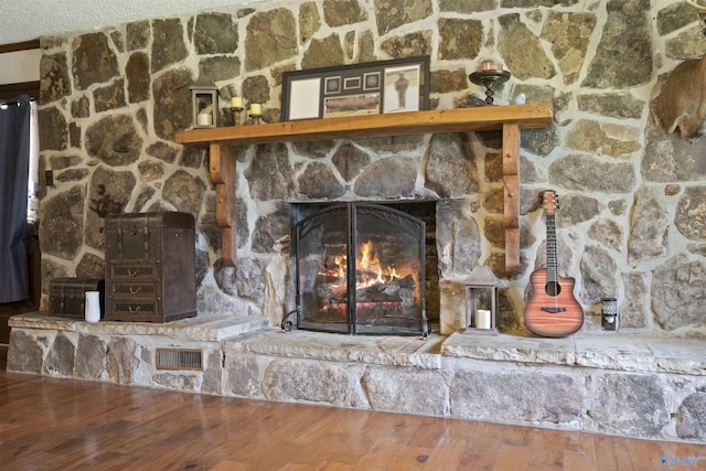 details featuring a stone fireplace, wood finished floors, and visible vents