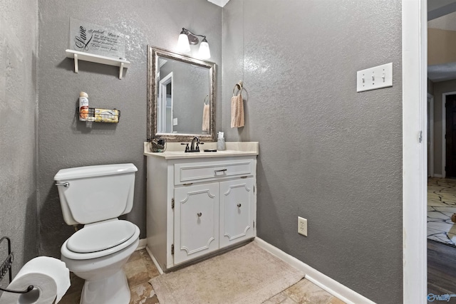 bathroom featuring baseboards, a textured wall, and toilet