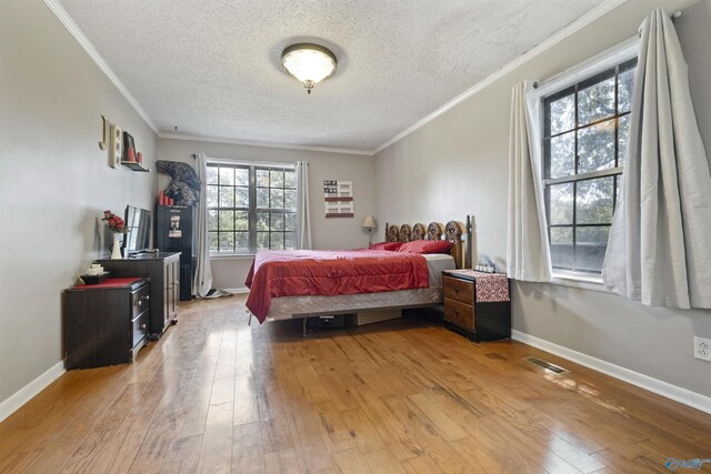 bedroom featuring light wood-type flooring, a textured ceiling, and crown molding