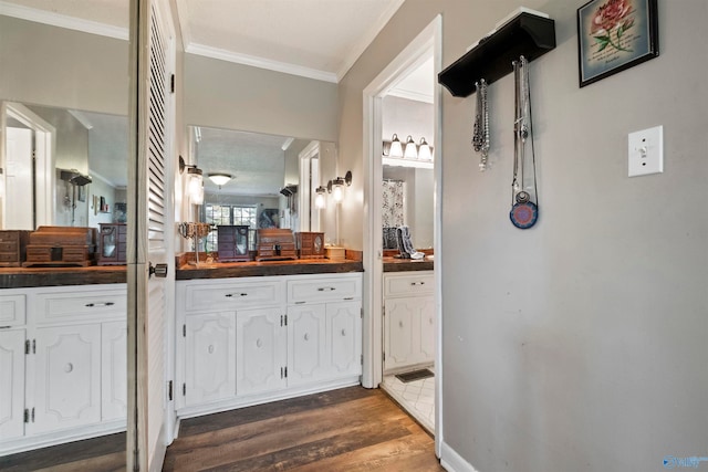 bathroom with crown molding, wood-type flooring, and vanity