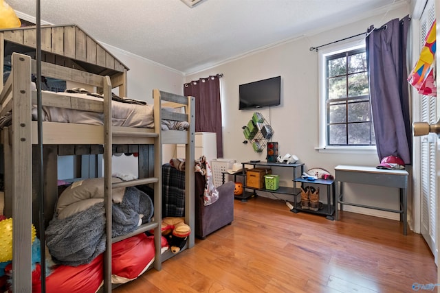 bedroom with hardwood / wood-style floors, ornamental molding, and a textured ceiling