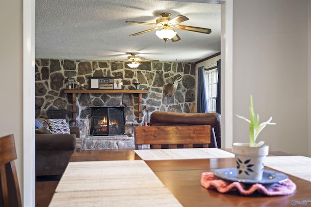 dining space with a fireplace, a textured ceiling, and ceiling fan