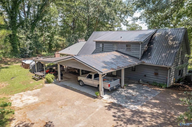 view of front of home featuring metal roof, an attached carport, concrete driveway, and a front yard