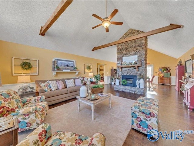 living room featuring hardwood / wood-style flooring, a stone fireplace, lofted ceiling with beams, and a textured ceiling