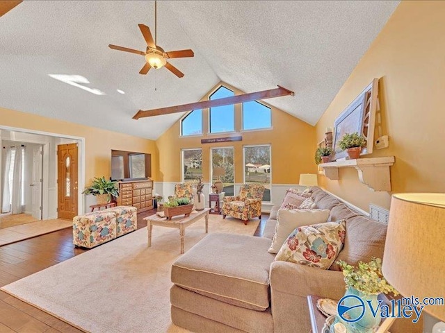 living room with ceiling fan, wood-type flooring, a textured ceiling, and vaulted ceiling