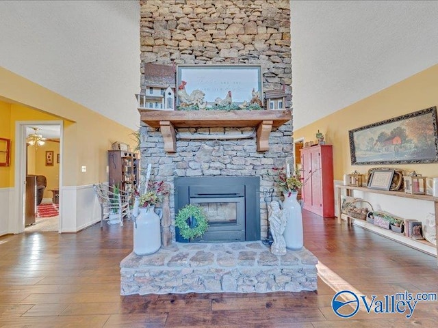 living room featuring lofted ceiling, dark wood-type flooring, a fireplace, and a textured ceiling