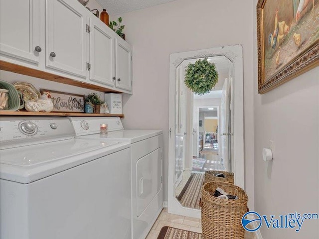 clothes washing area with separate washer and dryer, light tile patterned floors, cabinets, and a textured ceiling