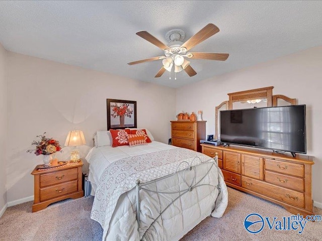 bedroom featuring a textured ceiling, light colored carpet, and ceiling fan
