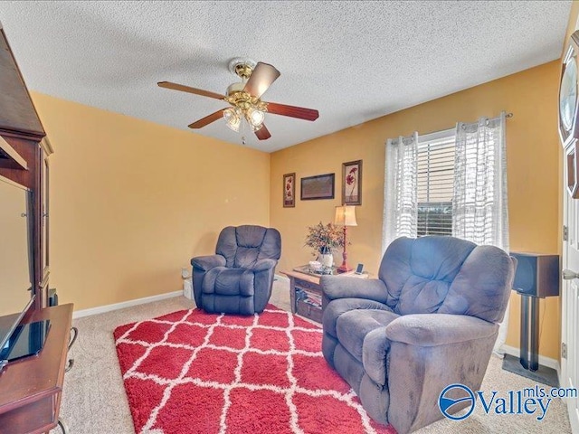 living area with ceiling fan, carpet floors, and a textured ceiling