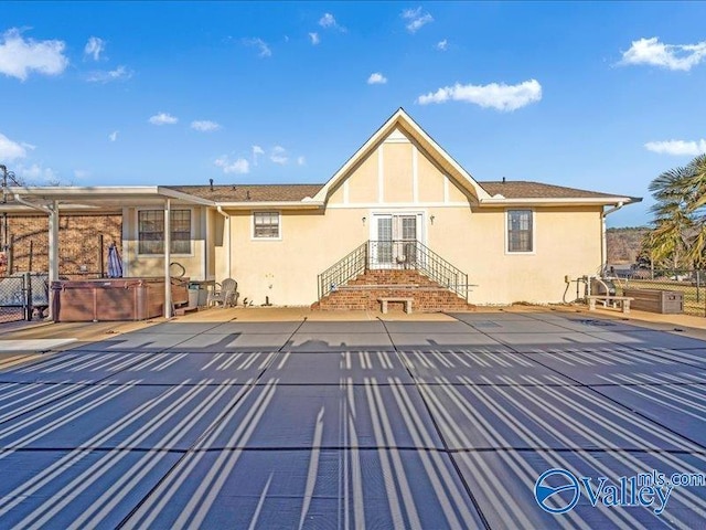 rear view of property featuring a hot tub