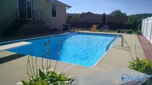 view of pool with a patio and a diving board