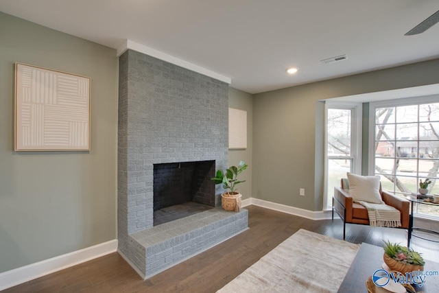 living room featuring dark hardwood / wood-style flooring and a brick fireplace