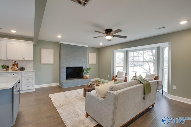 living room with ceiling fan, dark hardwood / wood-style floors, and a brick fireplace