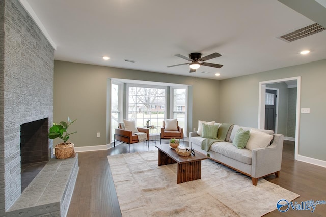 living room with a fireplace, wood-type flooring, and ceiling fan