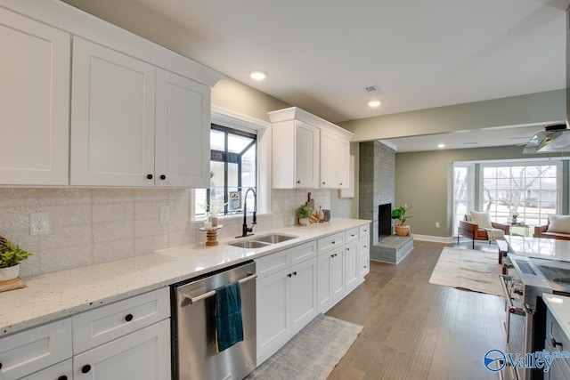 kitchen featuring sink, light hardwood / wood-style flooring, appliances with stainless steel finishes, white cabinetry, and light stone countertops