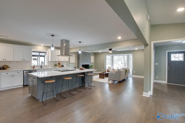 kitchen with hanging light fixtures, island exhaust hood, a center island, and white cabinetry