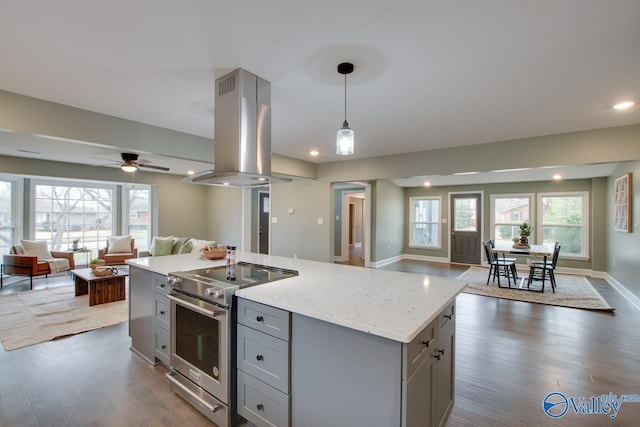 kitchen featuring stainless steel range with electric stovetop, island range hood, hanging light fixtures, a kitchen island, and light stone countertops