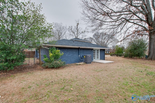 rear view of house with french doors, central AC unit, and a lawn