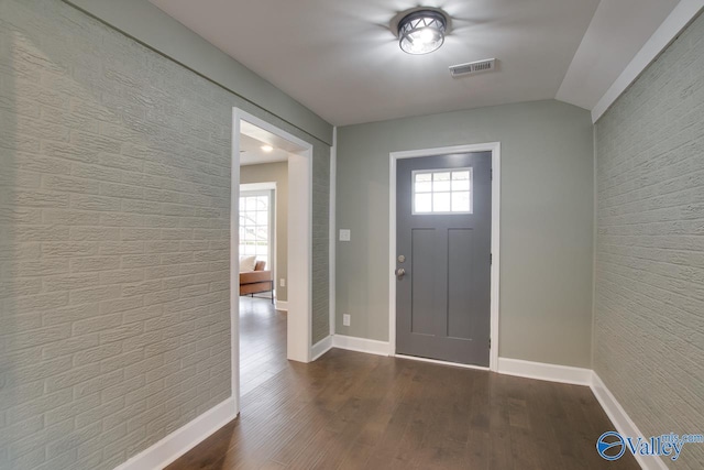 entrance foyer with brick wall, a healthy amount of sunlight, and dark hardwood / wood-style flooring