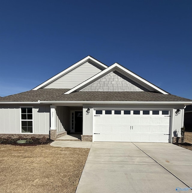 view of front facade featuring an attached garage, brick siding, a shingled roof, concrete driveway, and board and batten siding