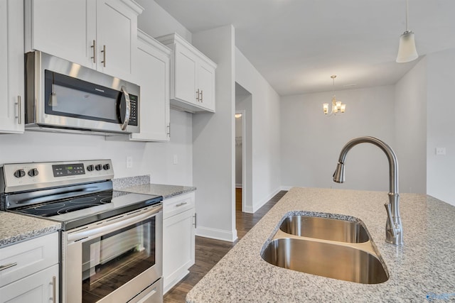 kitchen with dark wood-type flooring, light stone counters, appliances with stainless steel finishes, white cabinets, and a sink