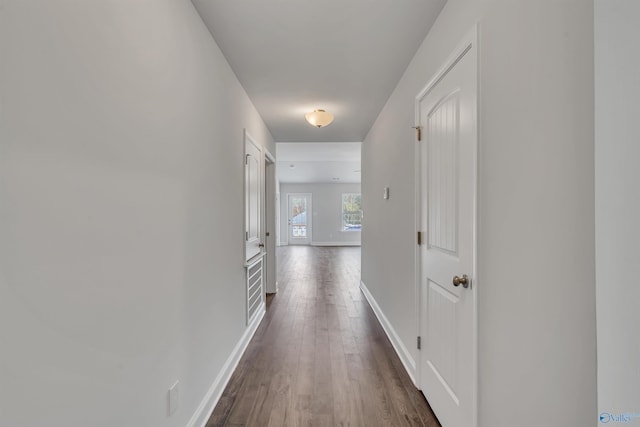 corridor featuring dark wood-style floors and baseboards