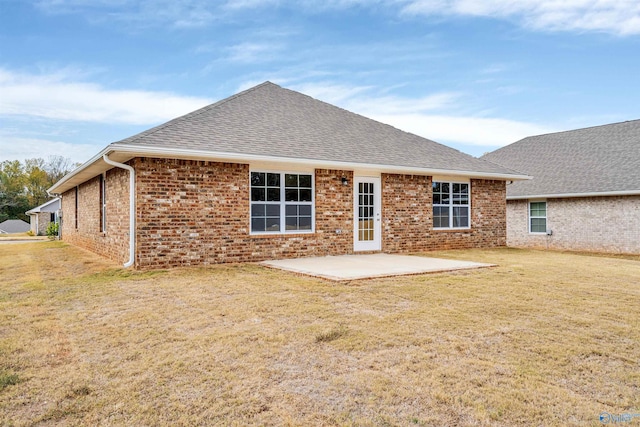 back of property featuring a yard, a patio, brick siding, and roof with shingles