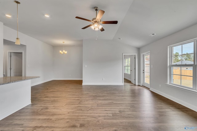 unfurnished living room featuring visible vents, lofted ceiling, ceiling fan with notable chandelier, wood finished floors, and baseboards