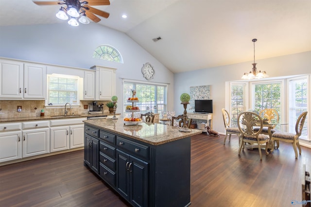 kitchen with ceiling fan with notable chandelier, white cabinetry, a healthy amount of sunlight, and a kitchen island