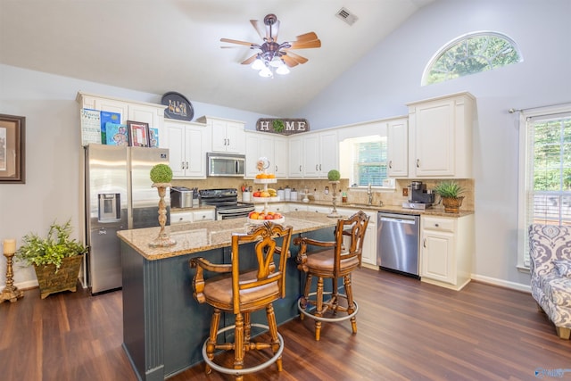 kitchen featuring high vaulted ceiling, a kitchen island, dark hardwood / wood-style flooring, stainless steel appliances, and ceiling fan