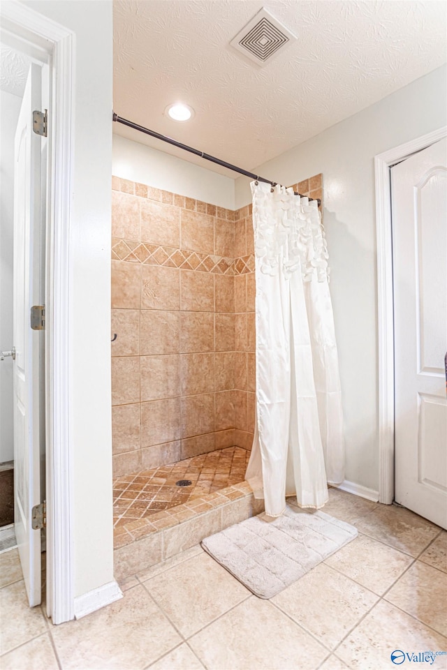 bathroom featuring a textured ceiling, tile patterned floors, and curtained shower