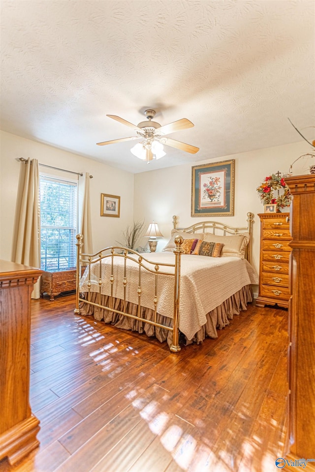 bedroom with ceiling fan, a textured ceiling, and hardwood / wood-style floors