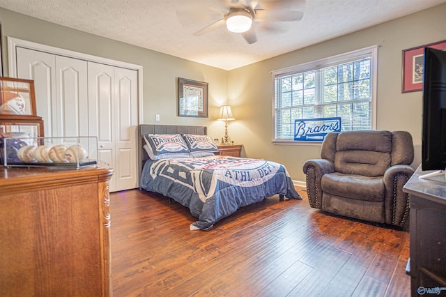 bedroom with a textured ceiling, dark hardwood / wood-style flooring, ceiling fan, and a closet