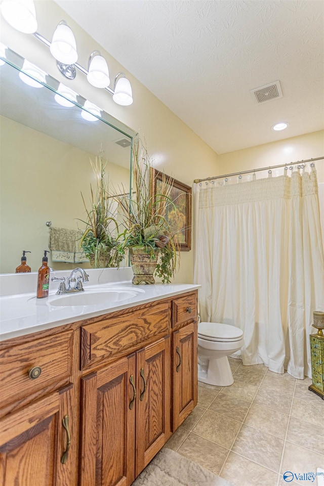 bathroom featuring vanity, tile patterned flooring, toilet, and a textured ceiling