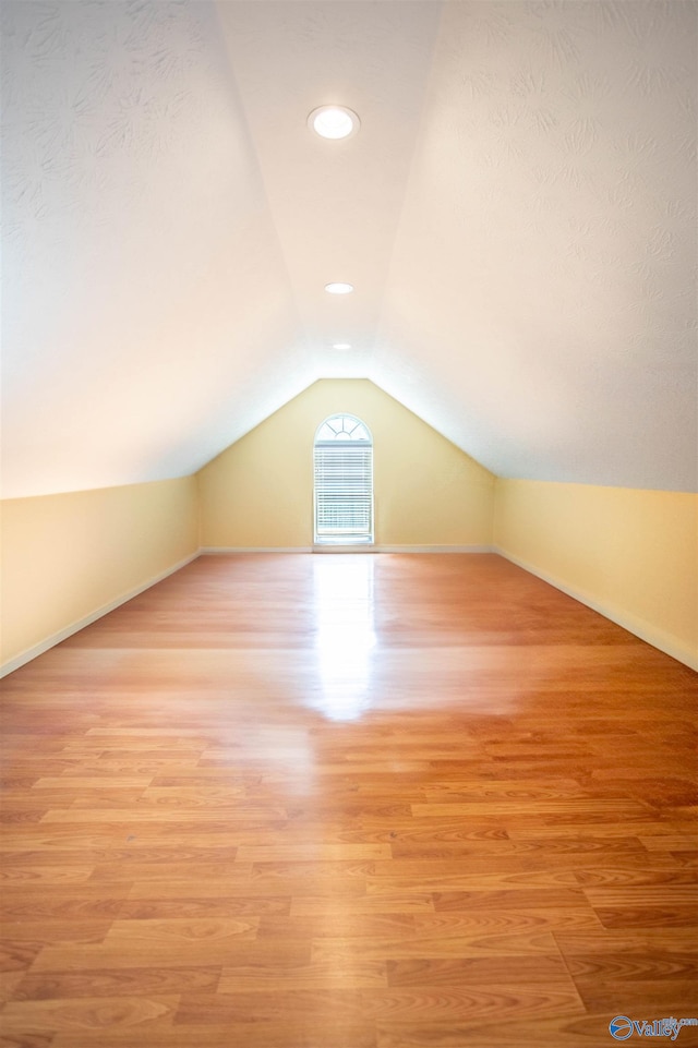 additional living space featuring light wood-type flooring and lofted ceiling