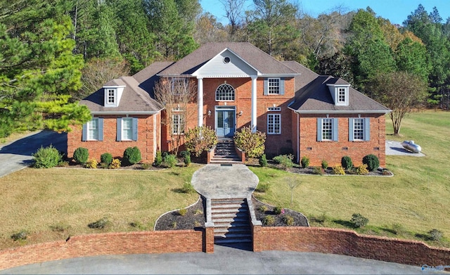 neoclassical / greek revival house featuring stairs, brick siding, crawl space, and a front yard