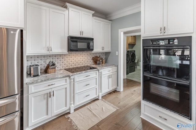 kitchen with crown molding, washing machine and dryer, black appliances, white cabinets, and decorative backsplash