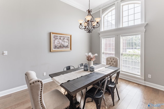 dining room featuring an inviting chandelier, hardwood / wood-style flooring, ornamental molding, and a towering ceiling