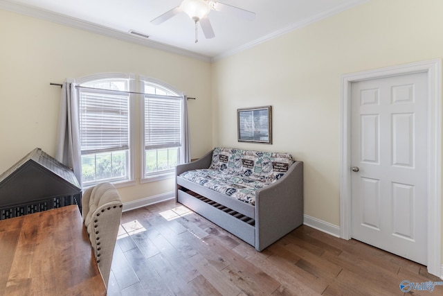 bedroom featuring light hardwood / wood-style flooring, ornamental molding, and ceiling fan