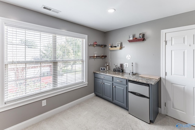 kitchen with stainless steel refrigerator, light carpet, and gray cabinetry