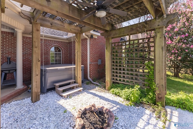 view of patio featuring ceiling fan, a hot tub, a pergola, and a fire pit