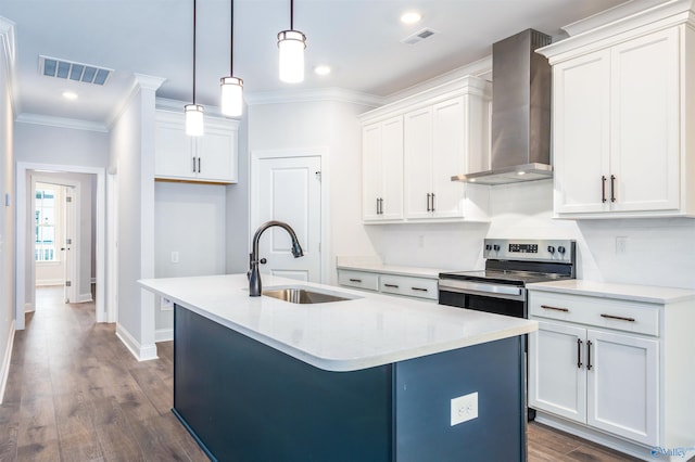 kitchen with pendant lighting, sink, stainless steel range with electric cooktop, a kitchen island with sink, and wall chimney range hood