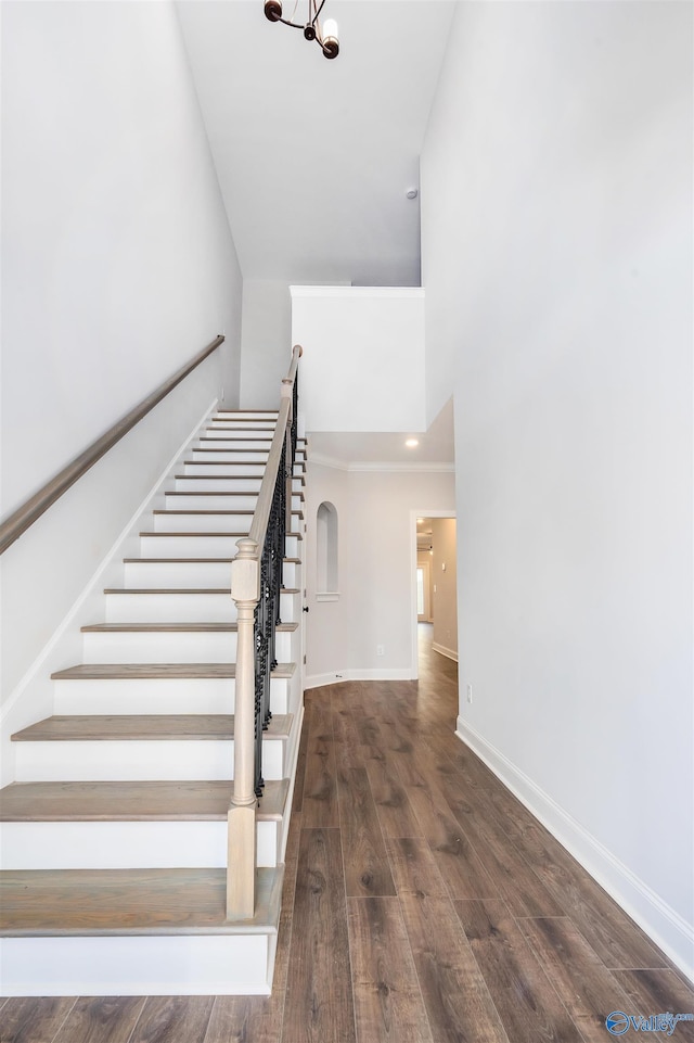 staircase featuring an inviting chandelier, hardwood / wood-style floors, and a high ceiling