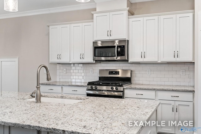 kitchen with decorative backsplash, ornamental molding, stainless steel appliances, white cabinetry, and a sink