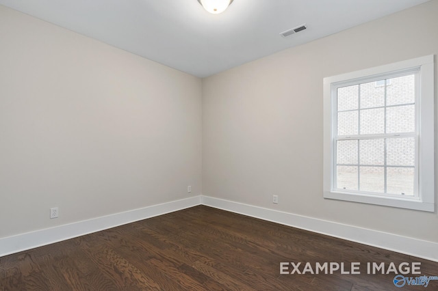 unfurnished room featuring visible vents, baseboards, and dark wood finished floors